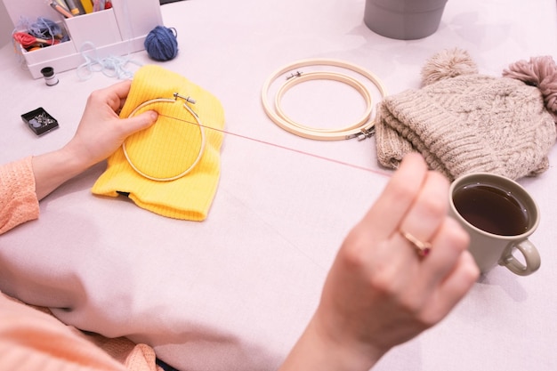 osoba haftująca przy stole